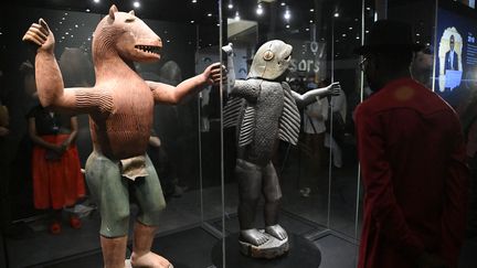 Un visiteur admire une statue à tête de lion représentant le roi Glèlè (à gauche) et une statue à tête humaine et corps de requin représentant le roi Behanzin, lors de l'exposition&nbsp;"Art du Bénin d'hier et d'aujourd'hui, de la restitution à la révélation",&nbsp;&nbsp;samedi 19 février 2022 à Cotonou (Bénin). (PIUS UTOMI EKPEI / AFP)