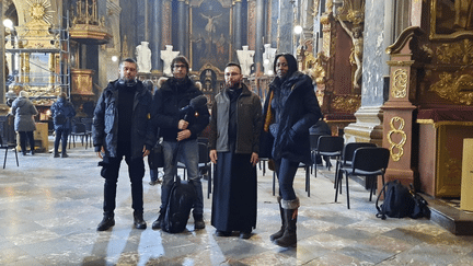 Le moine-soldat Roman, dans l’église Saint-Apôtres-Pierre-et-Paul de Lviv, le 15 mars, avec le fixeur, Fabien Gosset, technicien de reportage, et Sandrine Etoa-Andègue, reporter. "Roman, 26 ans, moine-soldat rencontré en l’église Saint-Apôtres-Pierre-et-Paul de Lviv, reçoit les confidences des soldats sur le front, notamment via les réseaux sociaux, Messenger, Instagram ou par SMS. Ils évoquent la dure réalité de la guerre sur le front, leur peur de la mort, leur foi. Le prêtre orthodoxe essaie de trouver les mots, des messages d’amour et un esprit guerrier, convaincu de la nécessité de la guerre et prêt à enlever sa soutane pour aller combattre. Il avait une voix très douce et déterminée." (SANDRINE ETOA ANDEGUE / FRANCEINFO / RADIO FRANCE)