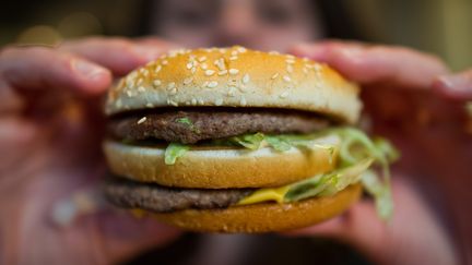 Une cliente déguste un Big Mac de la firme américaine McDonald's à Mühlheim am Main (Allemagne), le 22 avril 2015.&nbsp; (CHRISTOPH SCHMIDT / DPA)