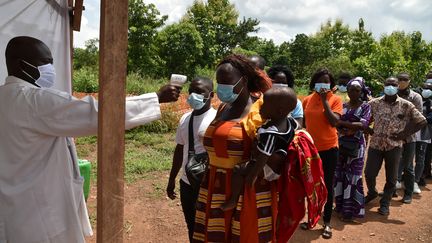 Des agents du ministère de la Santé de la Côte d’Ivoire mesurent la température corporelle des passagers à un poste de contrôle à l’entrée de Bouaké, le 25 juin 2020. (ISSOUF SANOGO / AFP)