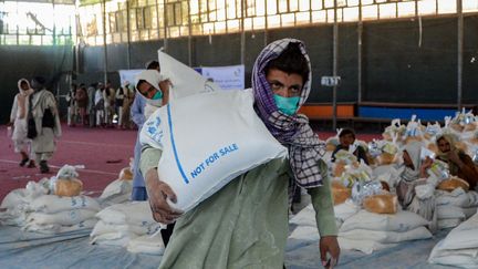 Un homme transporte un sac de céréales reçu dans une permanence du Programme alimentaire mondial (PAM) à Kandahar (Afghanistan), le 21 avril 2022. (JAVED TANVEER / AFP)