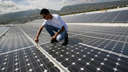 Une personne travaille sur le toit d'une entreprise o&ugrave; une centrale photovolta&iuml;que a &eacute;t&eacute; install&eacute;e,&nbsp;au Port, sur l'&icirc;le de la R&eacute;union, le 18 septembre 2008. (RICHARD BOUHET / AFP)