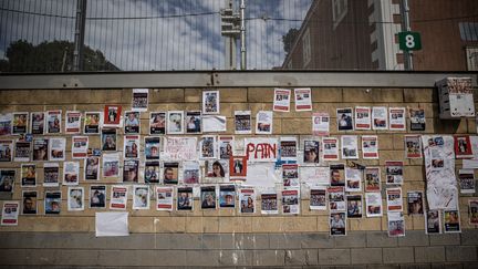 A Tel-Aviv, les photos des quelque 240 otages israéliens enlevés par le Hamas sont affichées sur un mur, le 18 octobre 2023. Onze jours plus tôt, le mouvement palestinien a mené une attaque terroriste contre l'Etat hébreu. Au total, plus de 1 200 personnes ont été tuées, pour la plupart des civils, affirment les autorités israéliennes. (MOSTAFA ALKHAROUF / ANADOLU / AFP)