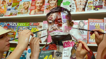 L'artiste chinois Liu Bolin en train de se fondre dans un kiosque à journaux, en Allemagne, en 2013.
 (Bernd Weissbrod / EPA / MaxPPP)