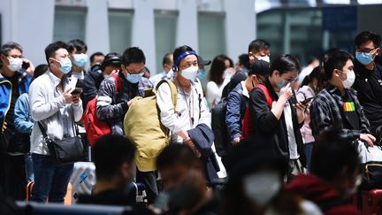 Des voyageurs, la plupart penchés sur leur téléphone portable, attendent leur train à la gare de&nbsp;Hangzhou dans la province du Zhejiang en Chine, le 30 avril 2020. (LONG WEI / MAXPPP)