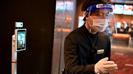 Un employé d'un cinéma vérifie les tickets des clients, à Tokyo, le 5 juin 2020. (CHARLY TRIBALLEAU / AFP)