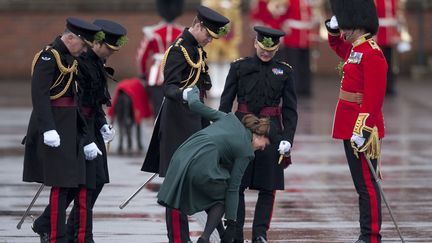 Le prince William aide son &eacute;pouse Catherine &agrave; retirer le talon de son escarpin pris dans une grille d'&eacute;vacuation lors d'une visite officielle &agrave; Aldershot (Royaume-Uni), le 17 mars 2013. (KIERAN DOHERTY / REUTERS)