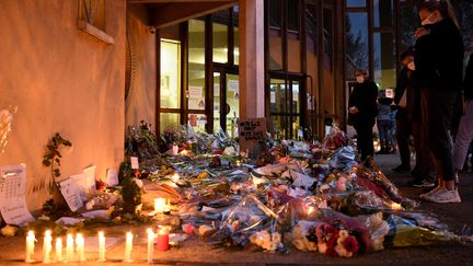 Des fleurs et des bougies déposées, le 17 octobre 2020, devant l'entrée du collège de Conflans-Sainte-Honorine (Yvelines), où enseignait Samuel Paty. (BERTRAND GUAY / AFP)