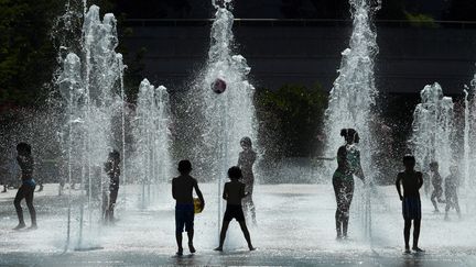 Des enfants jouent dans les jets d'eau au parc André-Citroën à Paris, le 26 juillet 2018. (ALAIN JOCARD / AFP)