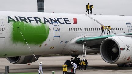 Des membres de l'ONG Greenpeace repeignent en vert un avion Air France à l'aéroport Roissy-Charles de Gaulle (Val-d'Oise), le 5 mars 2021.&nbsp; (ALAIN JOCARD / AFP)