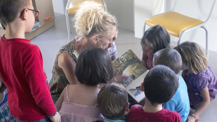 Des enfants de grande section de maternelle &eacute;coutent une animatrice leur lire une histoire, pendant le Temps d'activit&eacute;s p&eacute;riscolaires (TAP), le 8 septembre 2014 &agrave; Ferc&eacute;-sur-Sarthe (Sarthe). (VIOLAINE JAUSSENT / FRANCETV INFO)