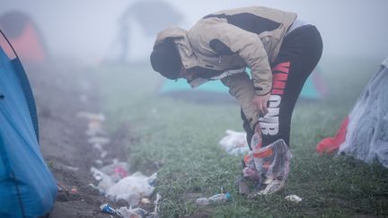 Un migrant enflie ses chaussures après avoir glissé ses pieds dans des sacs plastiques pour éviter qu'il ne soient trempés. Une forte pluie&nbsp;s'est abattue sur le camp, le 8 mars 2016. (KAY NIETFELD / DPA)