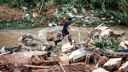 Un homme sur des débris d'immeubles après un glissement de terrain, à&nbsp;Bottlebrush, près de Durban (Afrique du Sud), le 23 avril 2019. (RAJESH JANTILAL / AFP)