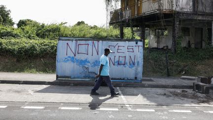 Un homme marche devant une inscription contre la vaccination du Covid-19, à Fort-de-France en Martinique, le 26 novembre 2021. (MAXPPP)