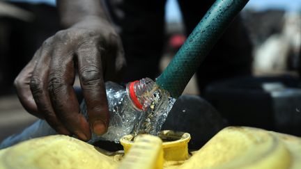 Un homme collecte de l'eau dans un jerrican, &agrave; Nairobi (Kenya), le 22 mars 2012. (TONY KARUMBA / AFP)