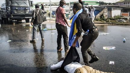  
Des supporteurs de Jean Ping tentent de dégager un camarade blessé lors des affrontements avec les forces de sécurité le 31 Août 2016 à Libreville. (Photo AFP/Marco Longari)