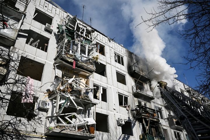 Les pompiers interviennent dans un immeuble touché par un missile, le 24 février 2022, à Chuguiv, dans le nord-est de l'Ukraine. (ARIS MESSINIS / AFP)