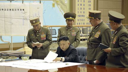 Cette photo a &eacute;t&eacute; diffus&eacute;e par l'agence officielle nord-cor&eacute;enne (KCNA), le 29 mars 2013. Le dirigeant Kim Jong-un consulte des documents, avec en arri&egrave;re-plan une carte d'op&eacute;rations militaires. (KNS / KCNA / AFP)