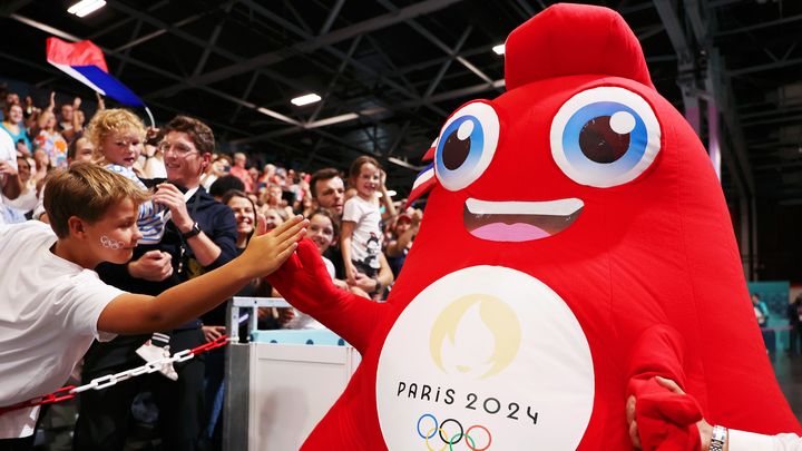 Une mascotte Phryge des Jeux de Paris 2024 salue un jeune spectateur du match de handball Croatie-Japon, à l'Arena Paris Sud de la porte de Versailles, le 27 juillet 2024. (CHRISTIAN PETERSEN / GETTY IMAGES EUROPE)