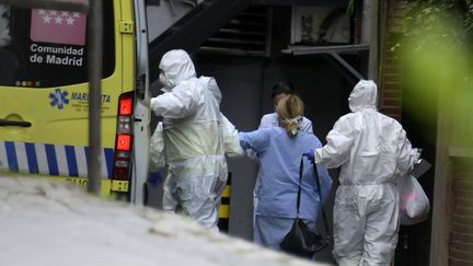 Des professionnels de santé escortent un patient à son arrivée au Gran Hotel Colon de Madrid (Espagne), un hôtel transformé en structure médicale pour traiter les cas les moins graves dans le cadre de l'épidémie provoquée par le nouveau coronavirus, le 19 mars 2020. (GABRIEL BOUYS / AFP)