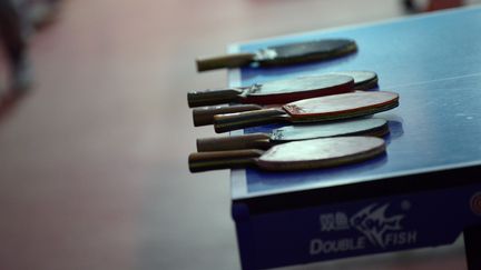 Des raquettes de tennis de table sont posées sur une table dans une école primaire en Chine, le 25 janvier 2016. (WANG ZHAO / AFP)