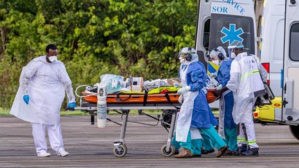 Le personnel médical transporte un patient infecté par le nouveau coronavirus dans un Airbus A400M sur la base aérienne guyanaise 367 à Matoury, près de Cayenne (Guyane), le 28 juin 2020. (JODY AMIET / AFP)