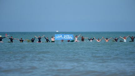 Des surfeurs lors d'une action de la campagne "Rame pour ta planète", dédiée à la protection des océans et de l'environnement, le 3 août 2019 à Bidart (Pyrénées-Atlantiques).&nbsp; (IROZ GAIZKA / AFP)