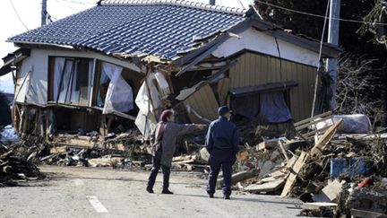 Des retraités regardent une maison déplacée après le tsunami, à Minamisoma, le 12 mars 2011. (AFP PHOTO / KAZUHIRO NOGI)