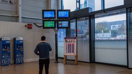 Un homme regarde des informations affichées sur des écrans à la gare de Lyon Part-Dieu, le 7 décembre 2022, lors d'une grève. Photo d'illustration. (OLIVIER CHASSIGNOLE / AFP)