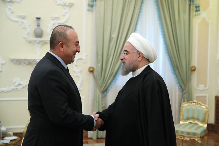 L'image d'une solide poignée de main entre le ministre turc des Affaires étrangères, Mevlüt Cavusoglu, et le président iranien, Hassan Rohani, le 26 novembre 2016 à Téhéran, en dépit des divergences et des méfiances réciproques entre leurs deux pays. (HO/IRANIAN PRESIDENCY/AFP)