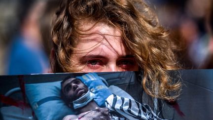 Une manifestante de l'opposition biélorusse tient la photo d'un homme blessé lors de la contestation contre Loukachenko. (SERGEI GAPON / AFP)