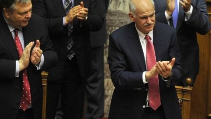 Le premier ministre grec, Georges Papandréou (à droite), en train d'applaudir après le vote de confiance du Parlement (AFP - LOUISA GOULIAMAKI)