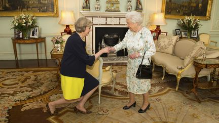 Theresa May effectue une révérence devant la reine Elizabeth II, quelques instants avant d'être investie&nbsp;Première ministre du Royaume-Uni, mercredi 13 juillet 2016 au Buckingham Palace de Londres. (DOMINIC LIPINSKI / REUTERS)