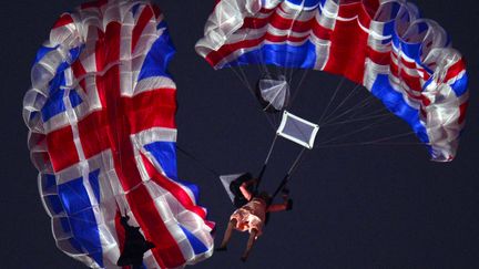 Un cascadeur symbolisant la Reine Elizabeth II saute en parachute au dessus du stade olympique de Londres lors de la cérémonie d'ouverture des JO 2012. (OLIVIER MORIN / AFP)