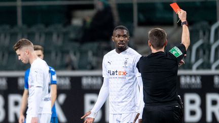 Le footballeur français Marcus Thuram écope d'un carton rouge pour avoir craché sur un adversaire, lors d'un match à domicile du&nbsp;Borussia Mönchengladbach&nbsp;(Allemagne), le 19 décembre 2020. (MARIUS BECKER / AFP)