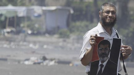 Un partisan du président islamiste, Mohamed Morsi, avec une affiche du dirigeant égyptien après des affrontements avec des manifestants laïcs à Giza, dans la banlieue du Caire (3-7-2013) (Reuters - Amr Abdallah Dalsh)