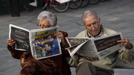 Un couple lit des journaux sportifs qui font leur une sur le "clasico" Barcelone-Real Madrid, le 11 d&eacute;cembre 2011, &agrave; Barcelone (Espagne).&nbsp; (EMILION MORENATTI / SIPA)