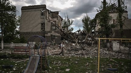 Un homme marche devant une école détruite dans la ville de Bakhmut, dans le Donbass, dans l'est de l'Ukraine, le 28 mai 2022, au 94e jour de l'invasion de l'Ukraine par la Russie. (ARIS MESSINIS / AFP)