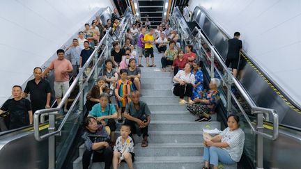 Des personnes se rafraîchissent dans une station de métro à Chongqing (Chine), le 24 juillet 2024. (CFOTO / NURPHOTO / AFP)