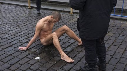 Un policier s'approche de l'artiste&nbsp;Pyotr Pavlensky alors que celui-ci s'est clou&eacute; les organes g&eacute;nitaux au sol afin deprotester contre "l'indiff&eacute;rence politique" de la soci&eacute;t&eacute; russe, Moscou (Russie), le 10 novembre 2013. (REUTERS)