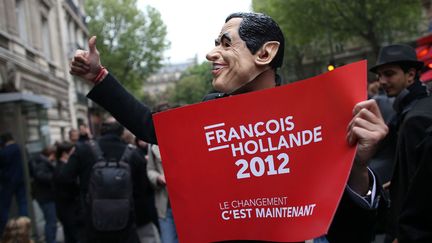 Un supporter de Fran&ccedil;ois Hollande d&eacute;file avec un masque de Nicolas Sarkozy &agrave; Paris. (THOMAS COEX / AFP)