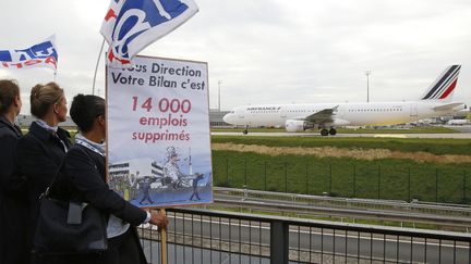 Des employ&eacute;s d'Air France manifestent au si&egrave;ge de la compagnie pr&egrave;s de l'a&eacute;roport de Roissy alors qu'un avion de la compagnie passe sur le tarmac, le 5 octobre 2015. (JACKY NAEGELEN / REUTERS)