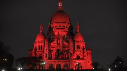 La basilique du Sacré-Cœur est illuminée en rouge au sommet de la butte Montmartre, dans le cadre de la campagne "Mercredi rouge", en hommage aux chrétiens persécutés dans le monde, le 24 novembre 2021, à Paris. (JULIEN DE ROSA / AFP)