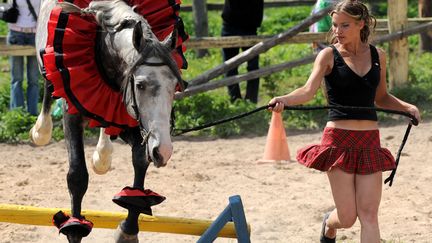 Une Bi&eacute;lorusse fait sauter un obstacle &agrave; une jument lors d'une f&ecirc;te de village &agrave; Zabolotiye (Bi&eacute;lorussie), le 6 ao&ucirc;t 2011. (VIKTOR DRACHEV / AFP)