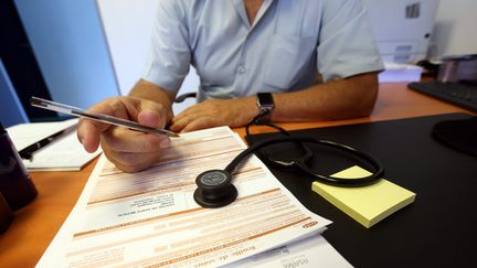 Un médecin signe un arrêt de travail. (LIONEL VADAM  / MAXPPP)