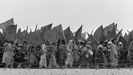 Les volontaires marocains participant à la Marche verte, le 7 novembre 1975, longent les fils barbelés de la frontière espagnole du Sahara occidental. Ce territoire passera sous administration marocaine avec l'accord hispano-marocco-mauritanien de Madrid du 14 novembre 1975. (GEORGES BENDRIHEM / AFP)