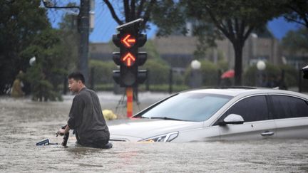 Un homme traverse une route inondée&nbsp;à Zhengzhou, dans la province d'Henan (Chine), le 20 juillet 2021. (MEITU / CHINATOPIX / AP)