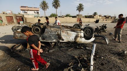 Des habitants &agrave; proximit&eacute; d'une voiture pi&eacute;g&eacute;e qui a explos&eacute; au sud de Bagdad (Irak), le 23 juillet 2012. (MOHAMMED AMEEN / REUTERS )