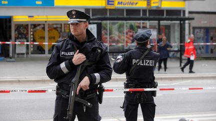 Des policiers allemands devant un supermarché de Hambourg (Allemagne) après l'attaque d'un homme armé d'un couteau qui a fait un mort, le 28 juillet 2017. (MARKUS SCHOLZ / DPA)