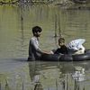 Une famille traverse une zone inondée, le 29 août 2022 à Charsadda (Pakistan). (ABDUL MAJEED / AFP)